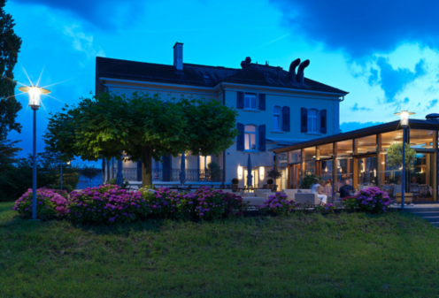 Stadt Restaurant bei Dämmerung mit leuchtenden Straßenleuchten im Vordergrund.